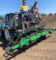 two people standing on variable rate applicator attached to back of tractor